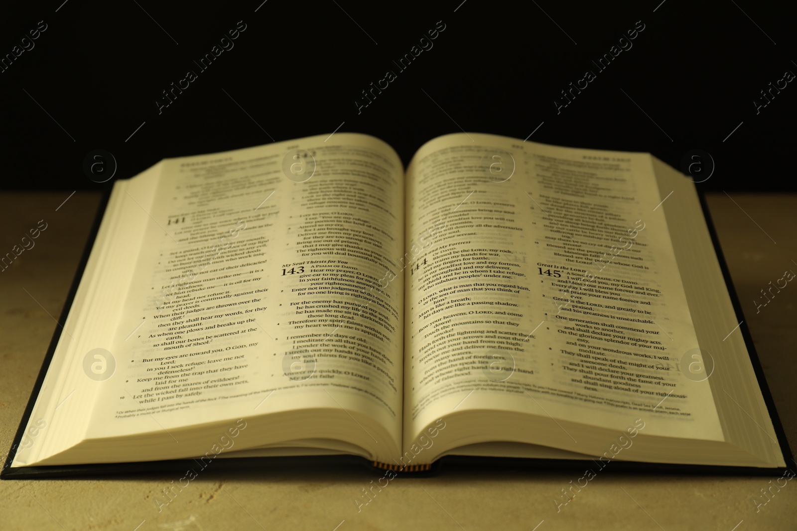 Photo of Open Holy Bible in English language on beige table