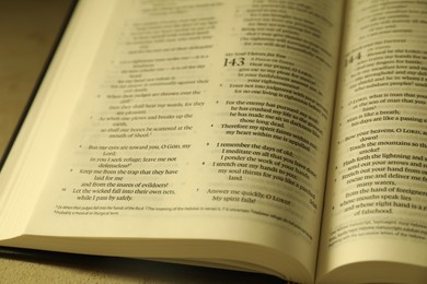 Open Holy Bible in English language on beige table, closeup