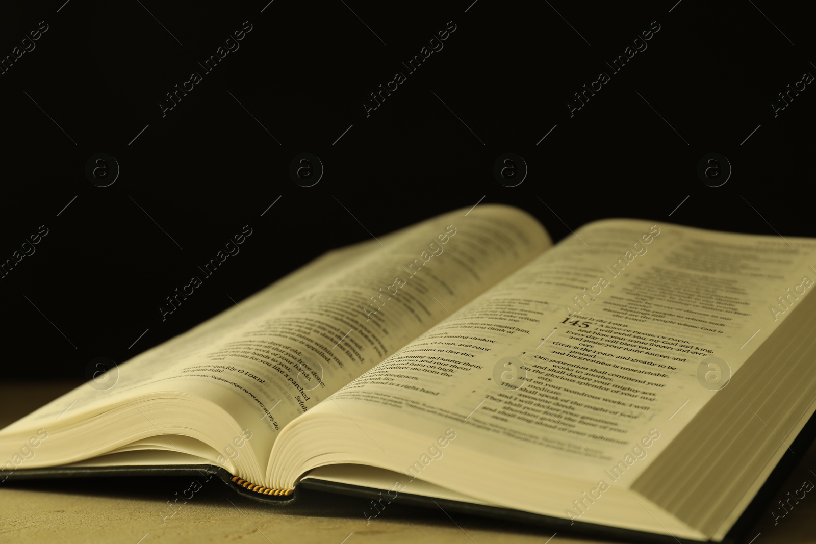 Photo of Open Holy Bible in English language on beige table, closeup