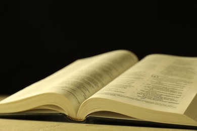 Open Holy Bible in English language on beige table, closeup