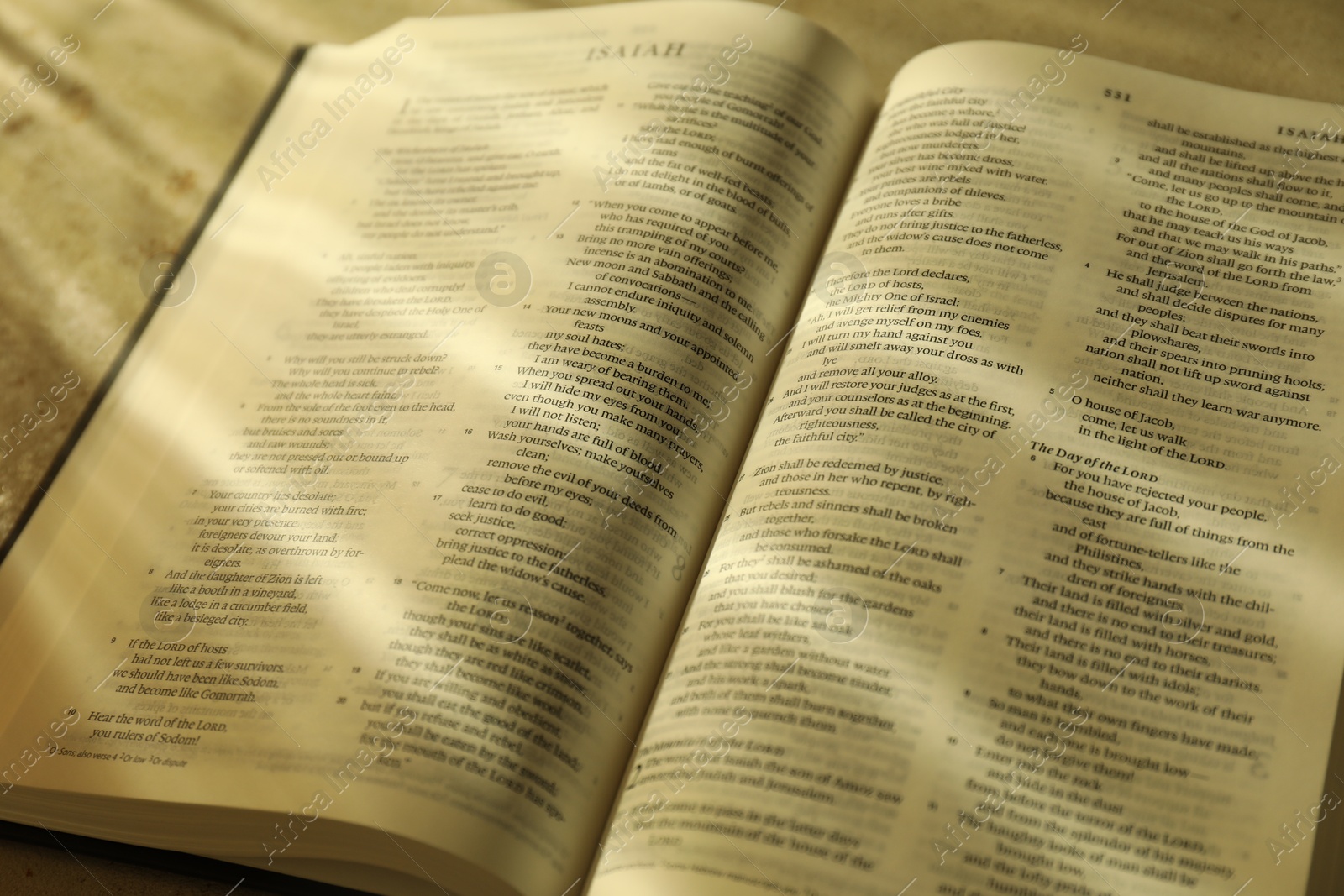 Photo of Open Holy Bible in English language on table, closeup