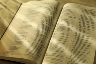 Photo of Open Holy Bible in English language on table, closeup