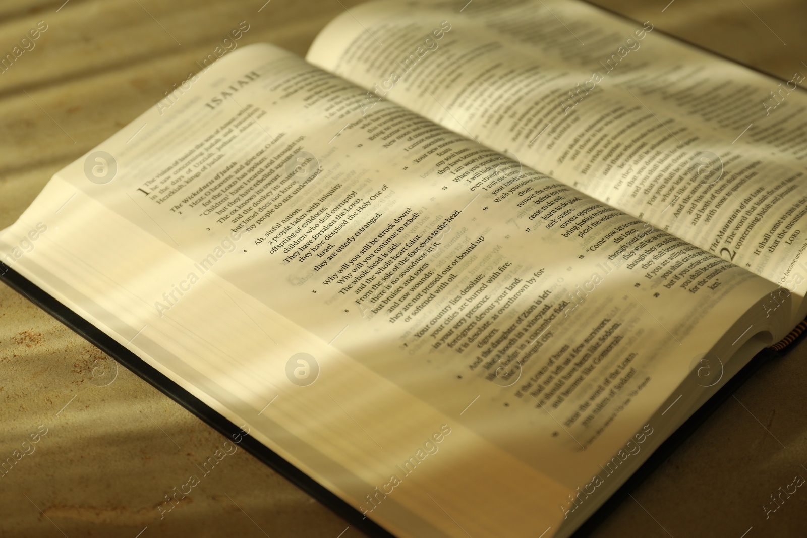 Photo of Open Holy Bible in English language on beige table, closeup