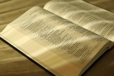 Photo of Open Holy Bible in English language on beige table, closeup