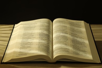 Photo of Open Holy Bible in English language on beige table, closeup