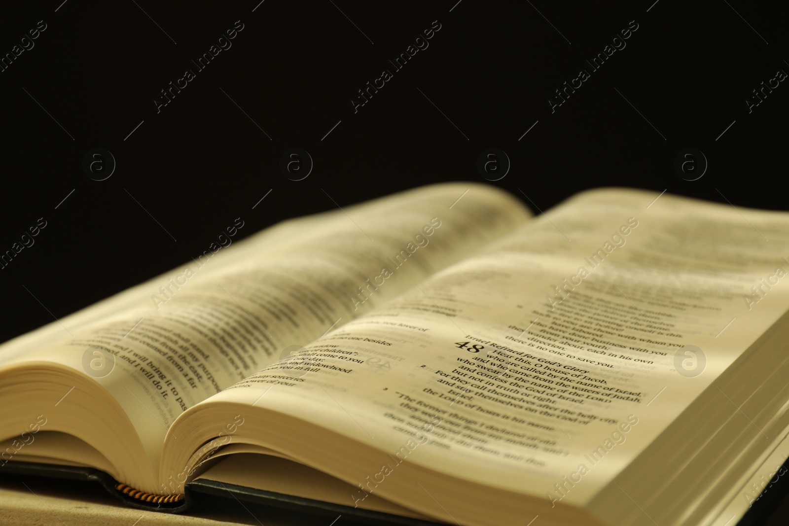 Photo of Open Holy Bible in English language on table, closeup