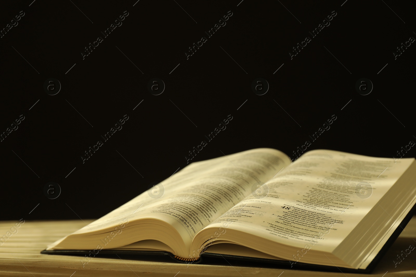 Photo of Open Holy Bible in English language on beige table