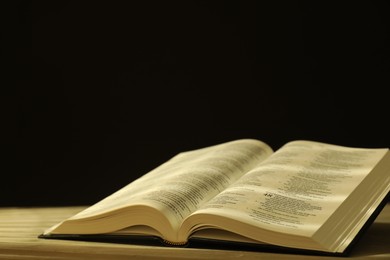 Photo of Open Holy Bible in English language on beige table