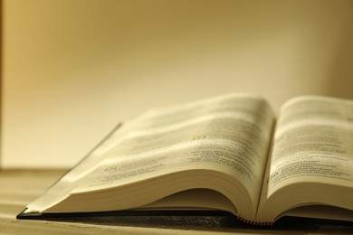 Photo of Open Holy Bible in English language on beige table, closeup