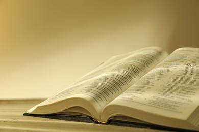 Photo of Open Holy Bible in English language on beige table, closeup