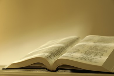 Photo of Open Holy Bible in English language on beige table, closeup