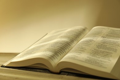 Photo of Open Holy Bible in English language on beige table, closeup