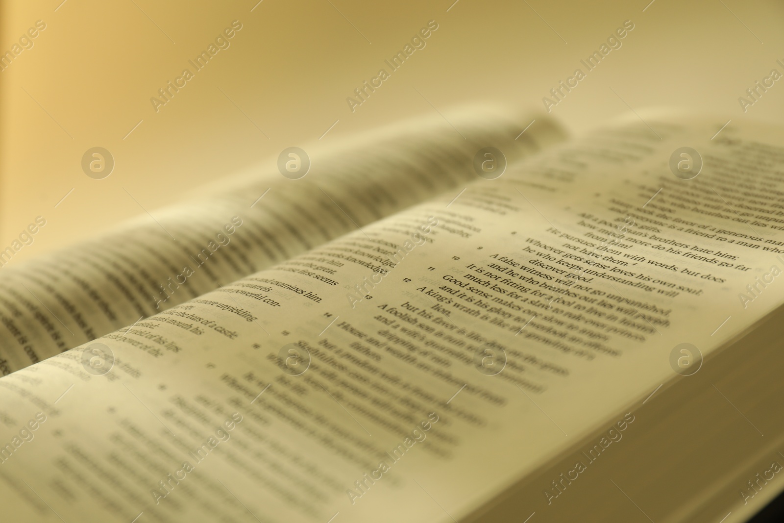 Photo of Open Holy Bible in English language against beige background, closeup