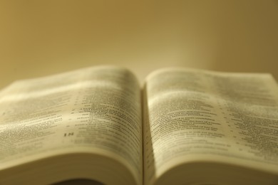 Photo of Open Holy Bible in English language against beige background, closeup