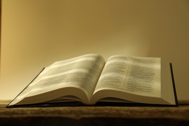 Photo of Open Holy Bible in English language on wooden table