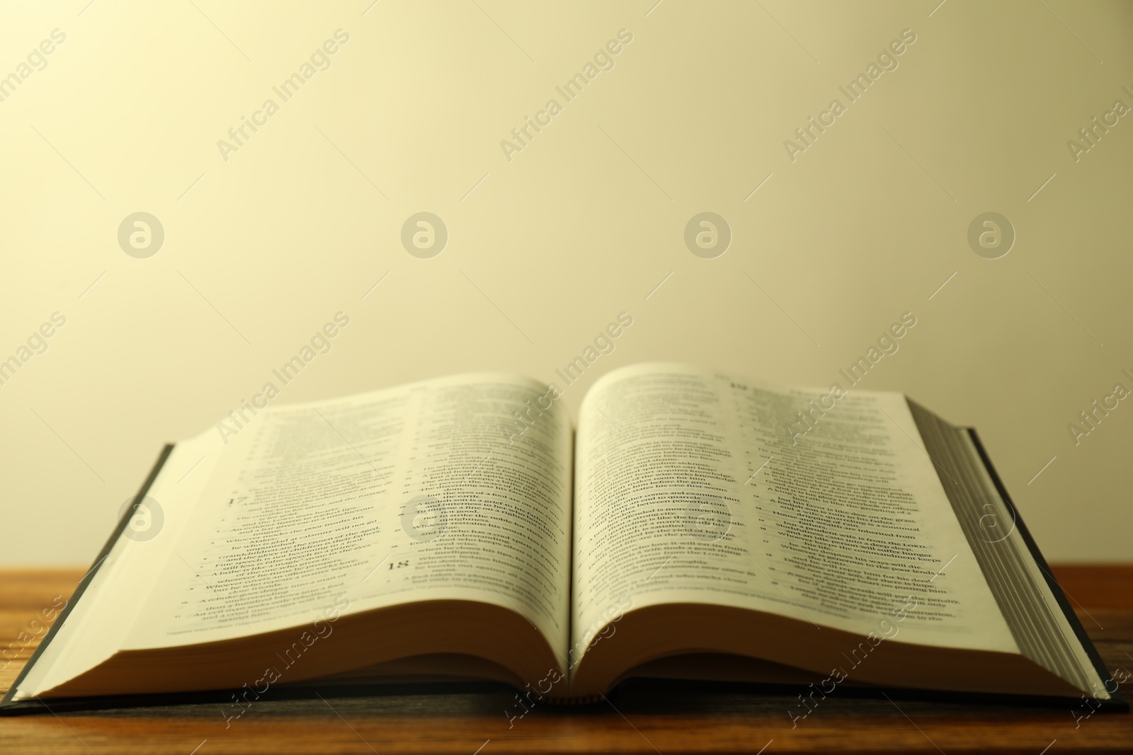 Photo of Open Holy Bible in English language on wooden table