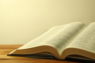 Photo of Open Holy Bible in English language on wooden table, closeup