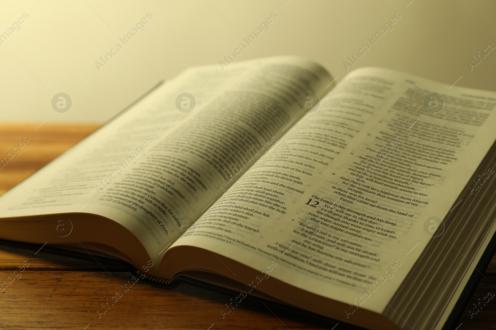 Photo of Open Holy Bible in English language on wooden table, closeup