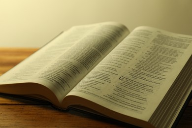 Photo of Open Holy Bible in English language on wooden table, closeup