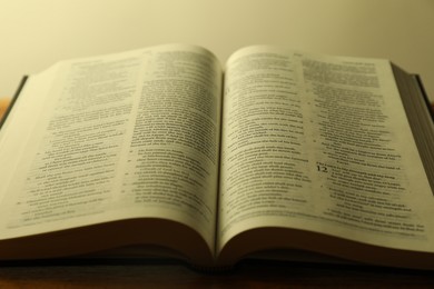 Open Holy Bible in English language on wooden table, closeup