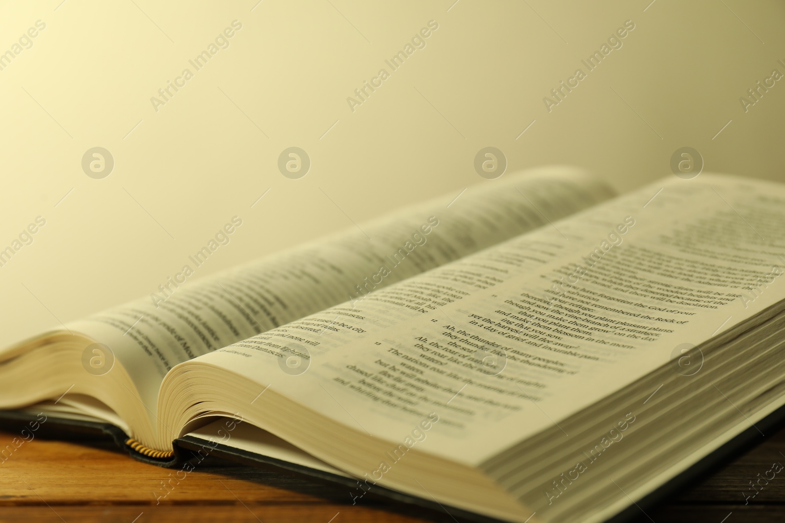 Photo of Open Holy Bible in English language on wooden table, closeup