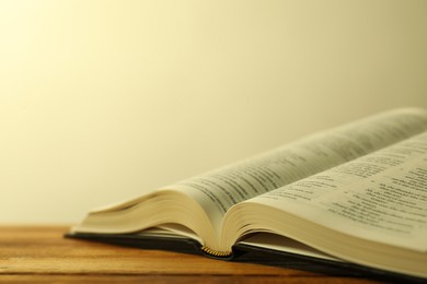 Photo of Open Holy Bible in English language on wooden table, closeup