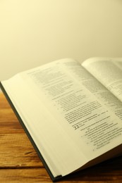 Photo of Open Holy Bible in English language on wooden table, closeup