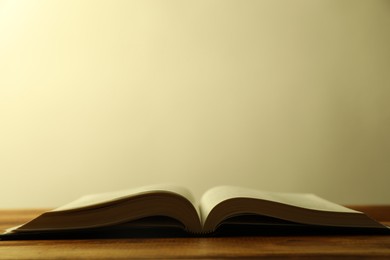 Photo of Open Holy Bible in English language on wooden table, closeup