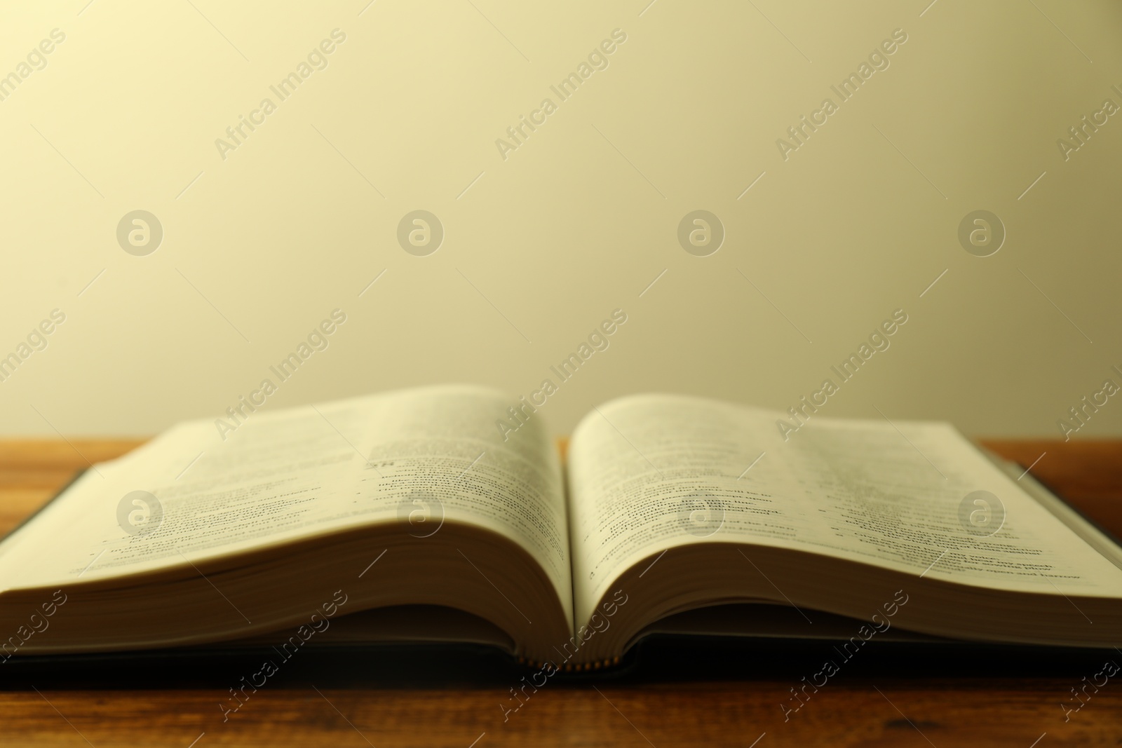 Photo of Open Holy Bible in English language on wooden table, closeup