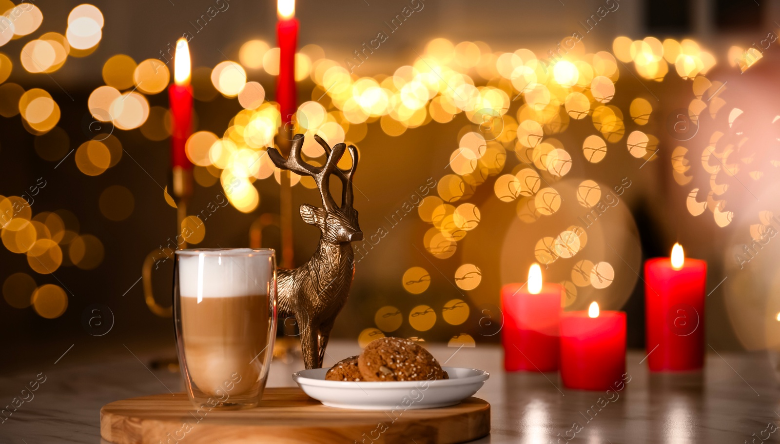 Photo of Aromatic coffee in glass, tasty cookies and burning candles on table against blurred Christmas lights. Bokeh effect