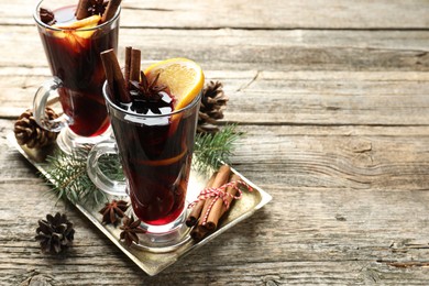 Photo of Tasty mulled wine with spices and Christmas decor on wooden table. Space for text