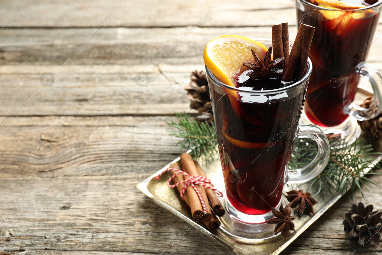 Photo of Tasty mulled wine with spices and Christmas decor on wooden table, closeup. Space for text