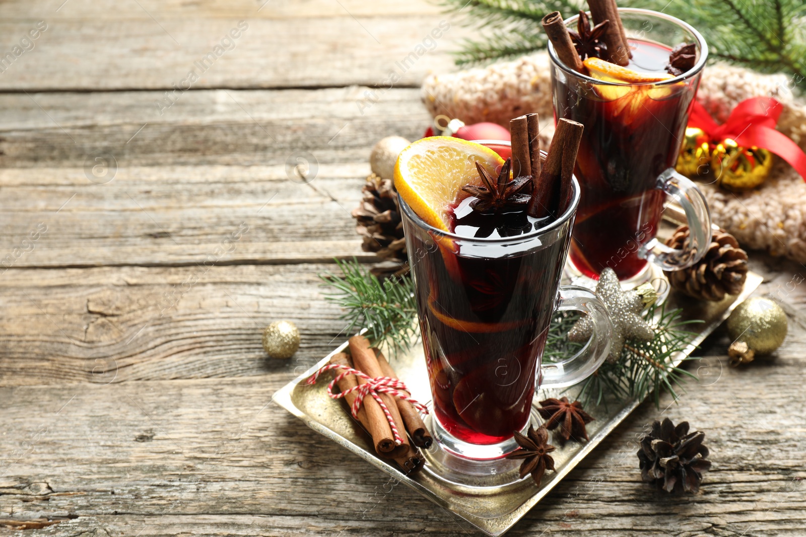 Photo of Tasty mulled wine with spices and Christmas decor on wooden table. Space for text