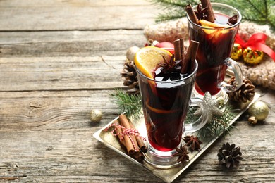 Photo of Tasty mulled wine with spices and Christmas decor on wooden table. Space for text