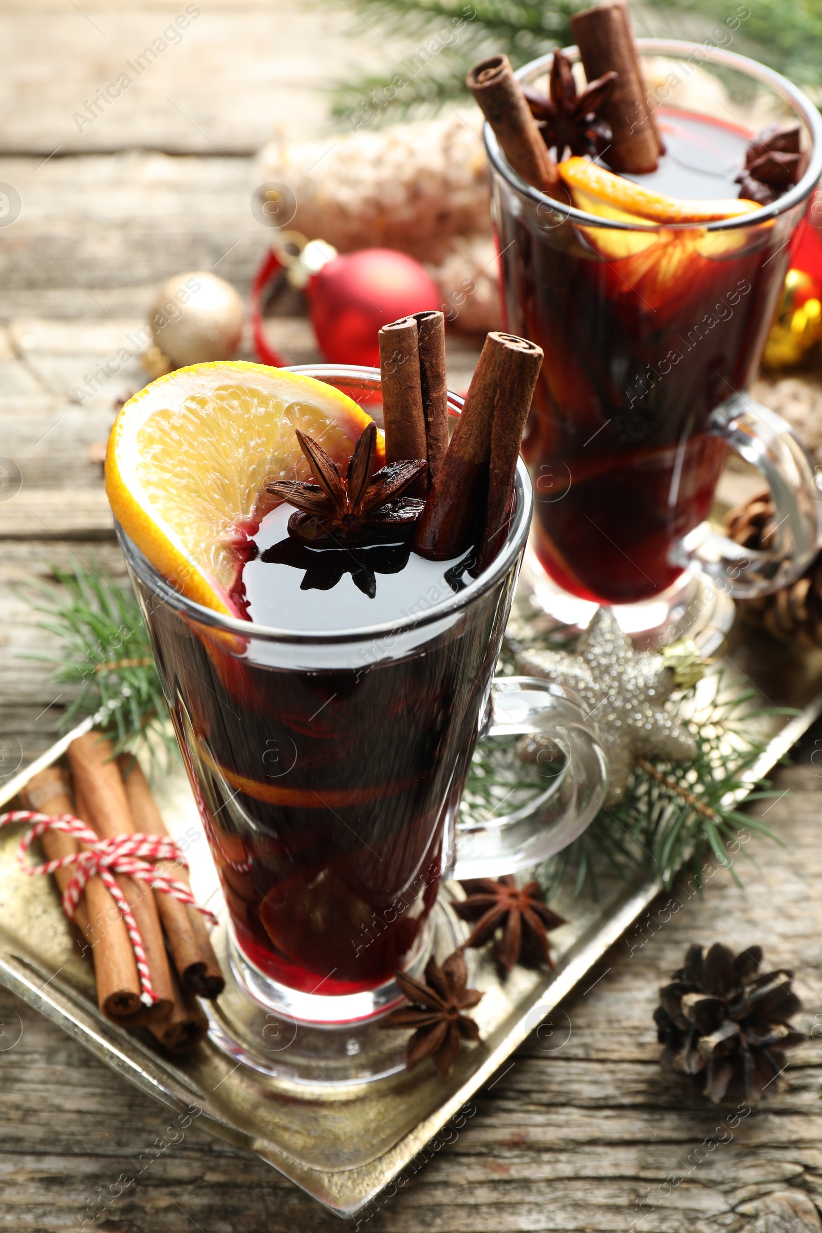 Photo of Tasty mulled wine with spices and Christmas decor on wooden table, closeup