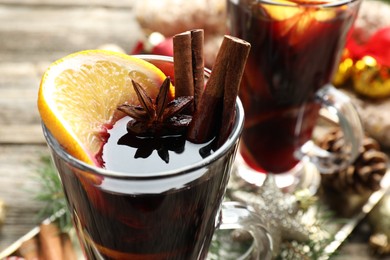 Photo of Tasty mulled wine with spices and Christmas decor on table, closeup