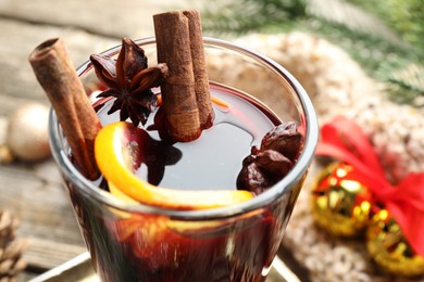 Photo of Tasty mulled wine with spices and Christmas decor on table, closeup