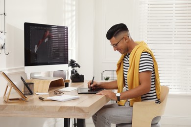 Photo of Professional retoucher working on graphic tablet at desk in office