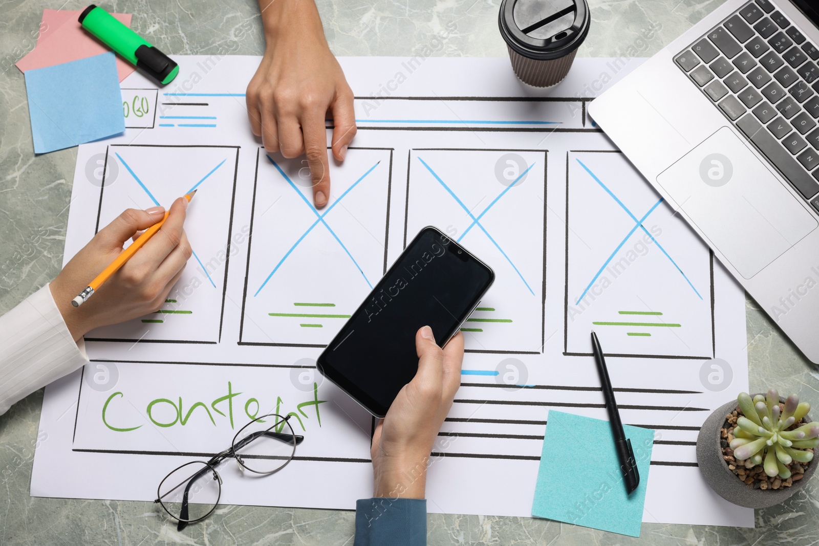 Photo of Developing UI design. Designers creating website wireframe on paper at grey marble table, top view