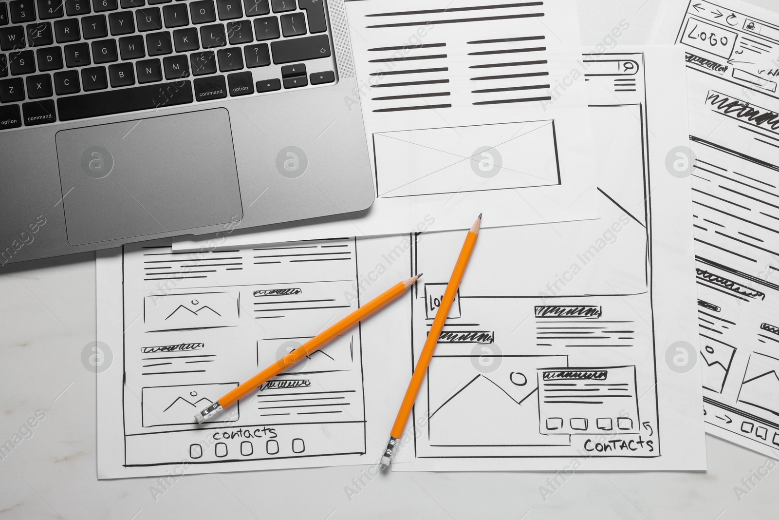 Photo of Developing UI design. Sketches of website wireframes, laptop and pencils on white marble table, top view