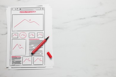 Photo of Developing UI design. Sketches of website wireframes and felt pen on white marble table, top view. Space for text