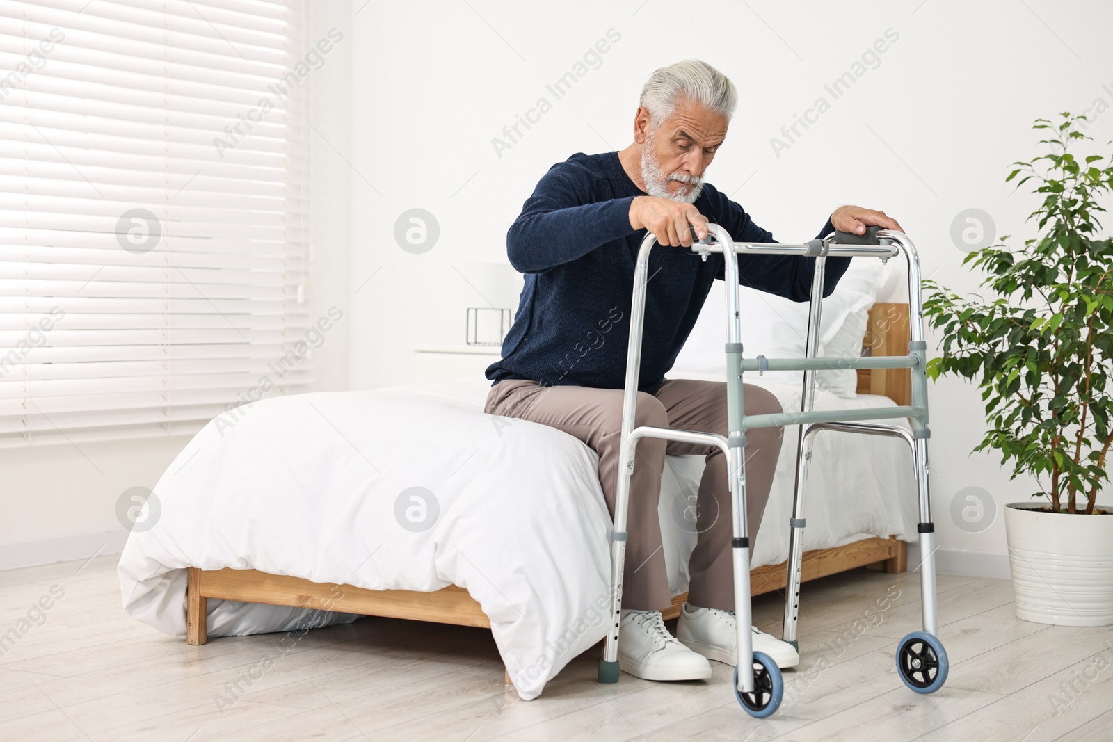 Photo of Senior man with walking frame on bed in hospital ward