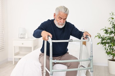 Senior man with walking frame on bed in hospital ward