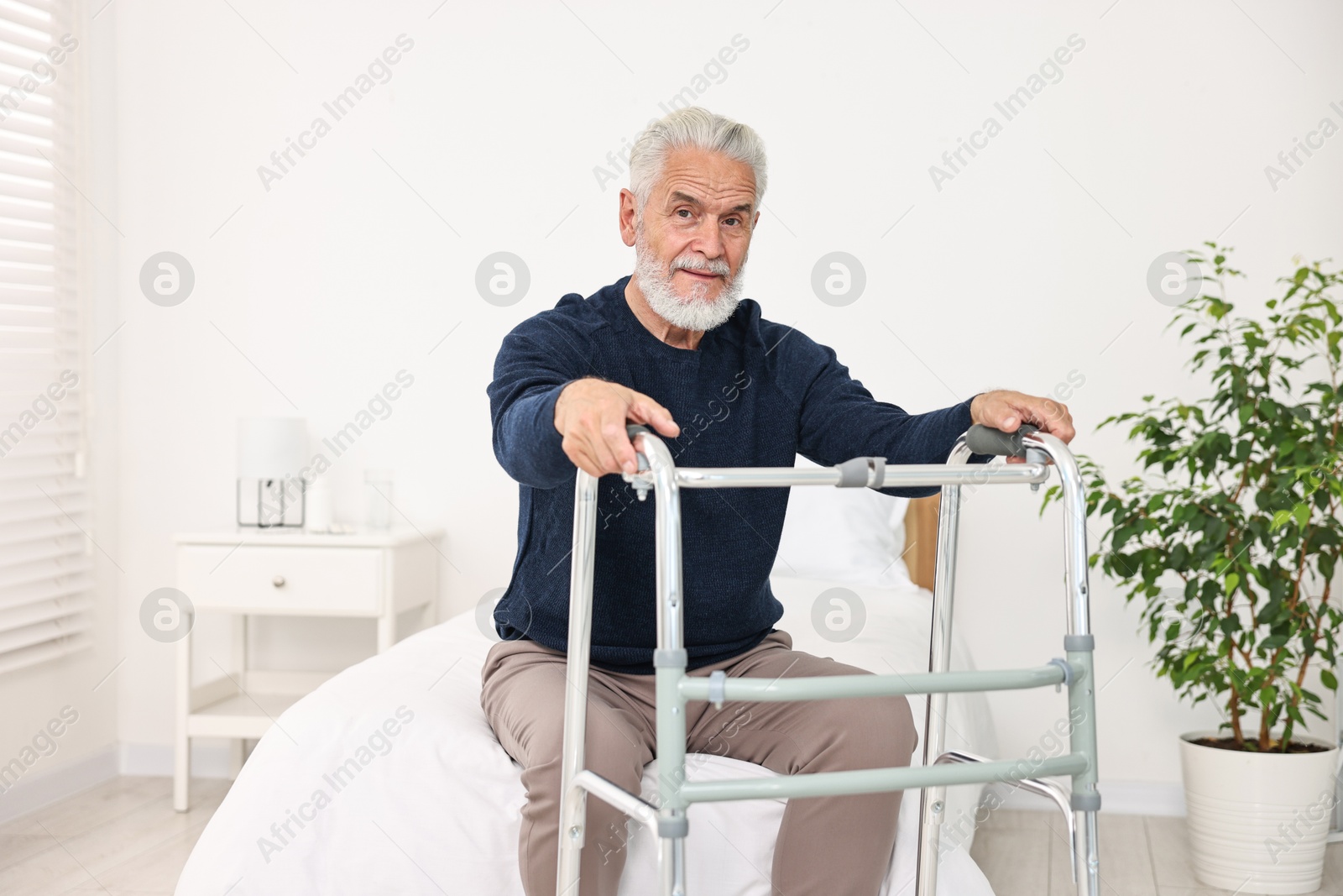 Photo of Senior man with walking frame on bed in hospital ward