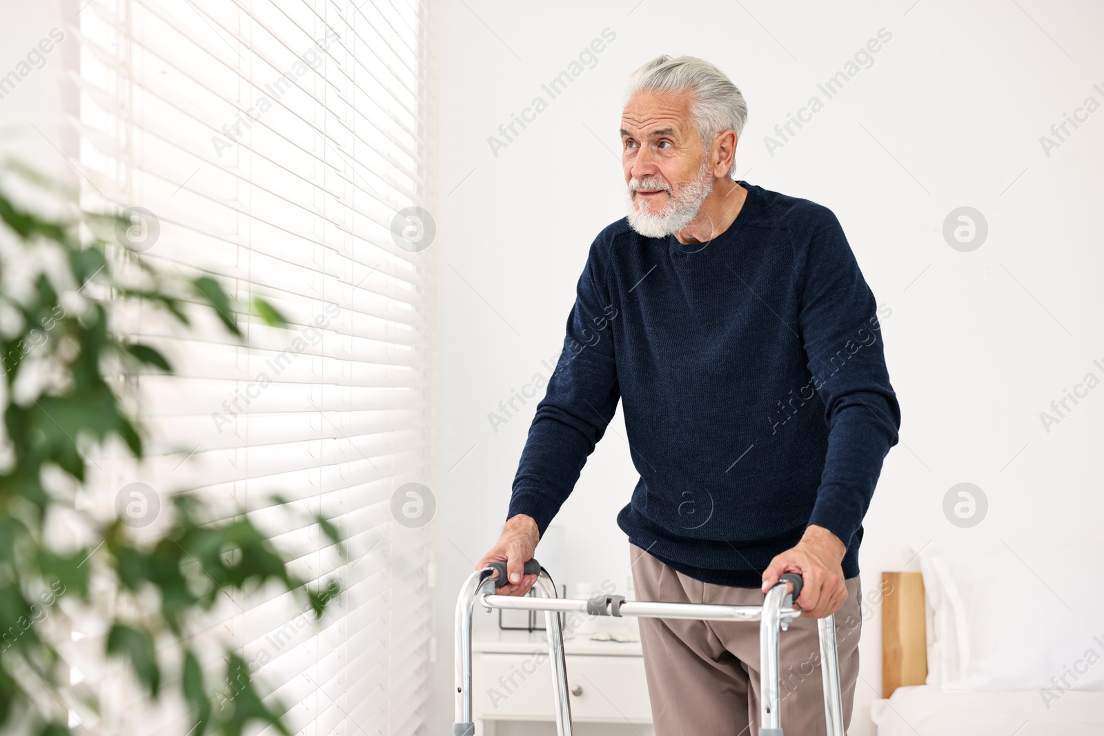 Photo of Senior man with walking frame in hospital ward