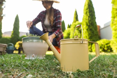 Photo of Woman with potted plant outdoors, focus on watering can