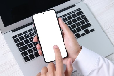 Photo of Man unlocking smartphone with fingerprint scanner near laptop at light wooden table, closeup