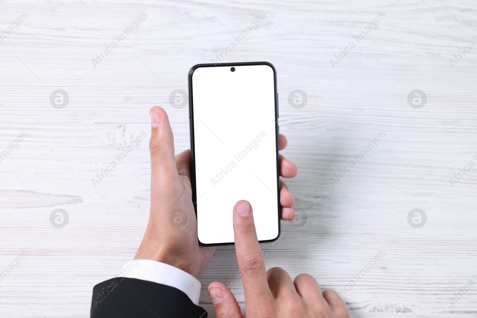 Photo of Man unlocking smartphone with fingerprint scanner at light wooden table, top view