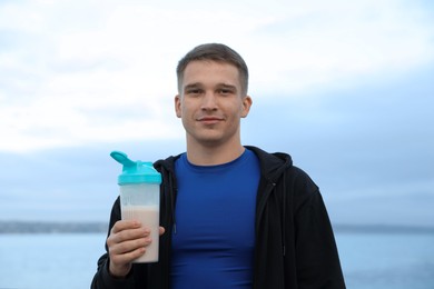 Photo of Athletic man with shaker of protein drink outdoors