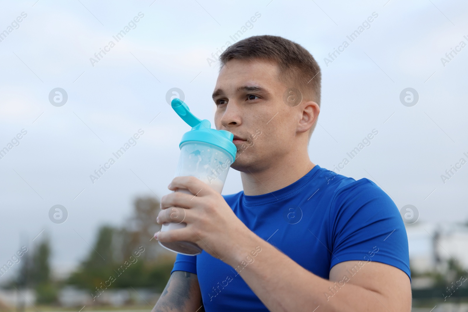 Photo of Handsome athletic man drinking protein shake outdoors